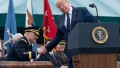 Fostul președinte SUA Donald Trump, aflat la tribună, dă mâna cu șeful Pentagonului, generalul Mark Milley, aflat pe un scaun