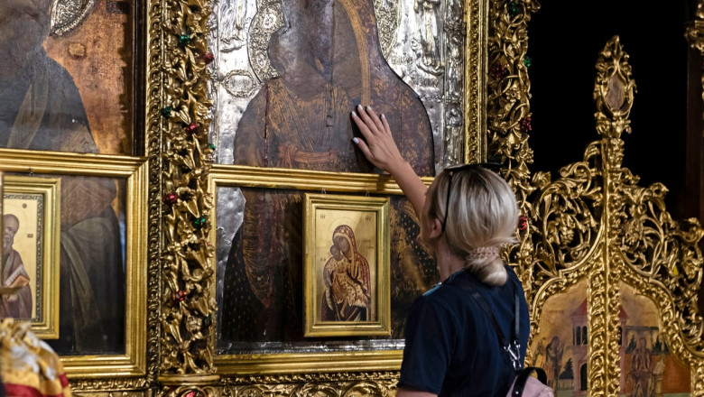 o femeie atinge icoana cu maica domnului dintr-o biserica