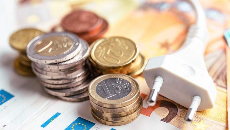 Bancnote și monede Euro și ștecherul unui cablu de alimentare cu electricitate