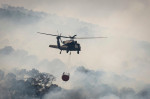 A Texas Army National Guard UH-60 Black Hawk helicopter drops water on the Hidden Pines Fire October 14, 2015 near Bastrop, Texas.