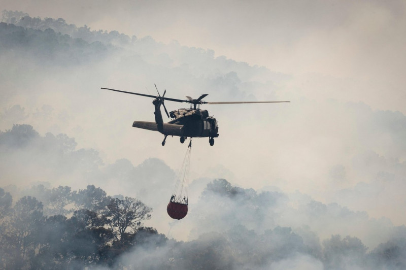 A Texas Army National Guard UH-60 Black Hawk helicopter drops water on the Hidden Pines Fire October 14, 2015 near Bastrop, Texas.