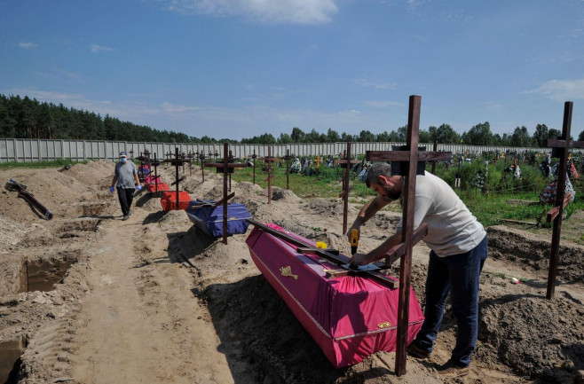 A communal worker places a plate with a number on a grave cross during the funeral of unidentified civilians who were killed by the Russian military, during the occupation of the city of Bucha. On Wednesday, 21 unidentified people who were killed by the R