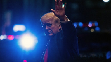 Donald Trump cu o lumină de far în spate face cu mâna