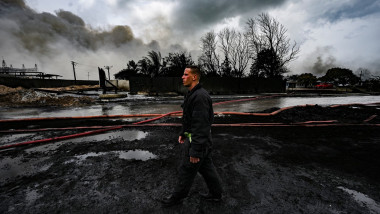un pompier se plimbă printr-o zonă distrusă de un incendiu