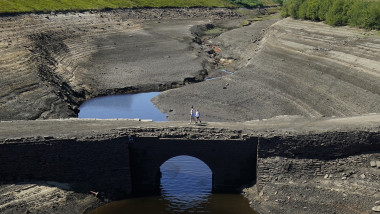 People walk across the dry cracked earth at Baitings Reservoir in Ripponden, West Yorkshire, where water levels are significantly low.