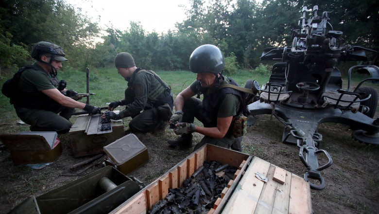 soldat ucraineni incarca mitraliere antiaeriene intr-o padure