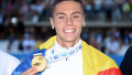 David Popovici are tricolorul pe umeri și arată medalia de aur.