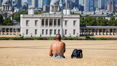 Un bărbat stă în iarba uscată din parcul Greenwich, Londra