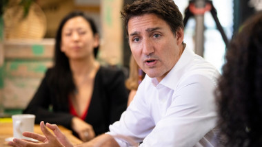 Premierul canadian Justin Trudeau sta la o masa si vorbeste cu o femeie