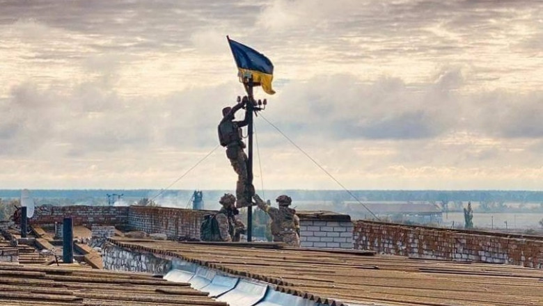 Soldați ucraineni ridică steagul țării pe un acoperiș din localitatea recucerită Vîsokopillea.