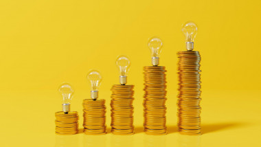 Rising energy cost concept. Light bulb on top of a stack of gold coins. 3D Rendering