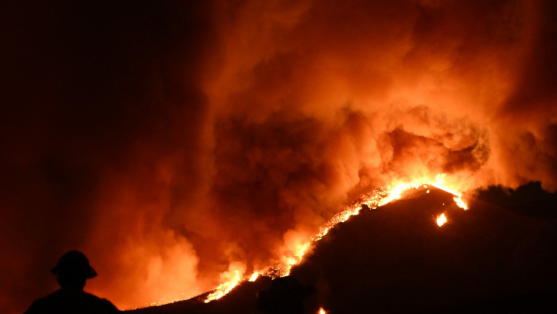 Incendiu masiv pe un deal și silueta unui pompier pe fundal