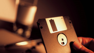 imagine cu o dischetă floppy disk ținută în mână