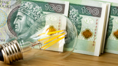 light bulb and Polish money, banknotes PLN 100 each, The concept of energy and electricity prices becoming more expensive with rising inflation