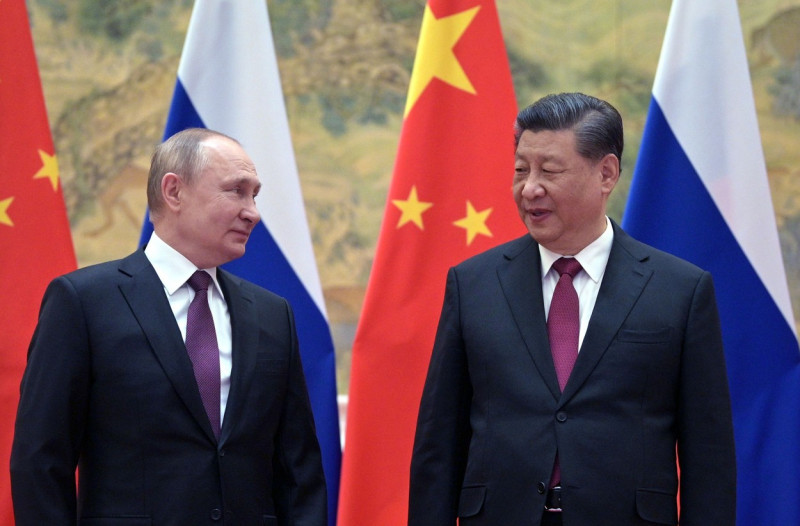 Putin și Xi se uită unul la celălalt cu steagurile Rusiei și Chinei în spate