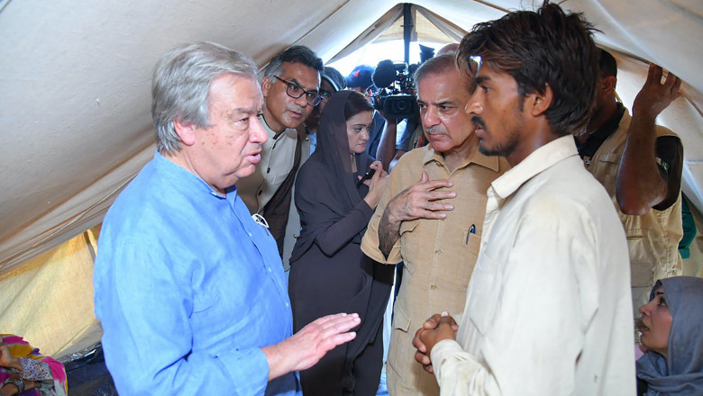 Primer Minister Shehbaz Sharif (C) and United Nations Secretary-General Antonio Guterres (L) meeting internally displaced people at a makeshift camp during their visit to flood-affected Usta Muhammad city in Jaffarabad district in Balochistan province