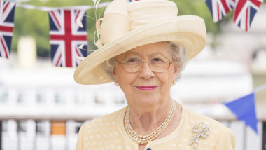 Queen lookalike Mary Reynolds wearing hat, pearls and glasses