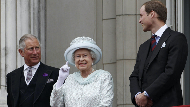 Queen Elizabeth II gesturing on the balcony of Buckingham Palace as Prince Charles and Prince William look on during the Diamond Jubilee celebrations in central London