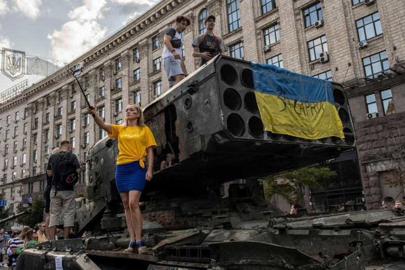 A woman takes a selfie as the people climb on the display of a destroyed Russian Multi Rocket Launch System Vehicle (MLRS) on the streets of Kyiv. As dedicated to the upcoming Independence Day of Ukraine, and nearly 6 months after the full-scale invasion