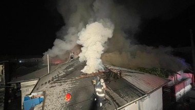 Pompier pe o casă care a luat foc.