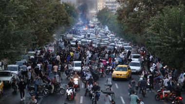 mulțime de oameni și incendiu cu fum negru pe o stradă din Iran