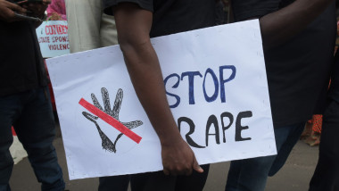 un barbat tine in mana un banner cu mesajul no rape