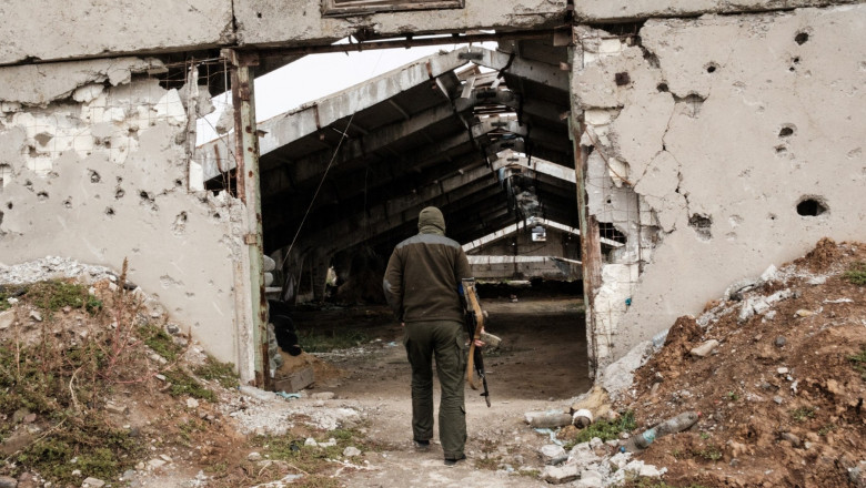 A Ukrainian soldier enters a destroyed building at an industrial chicken farm, near which the Russian forces were dug in, near a suspected mass grave in Kozacha Lopan, Kharkiv region