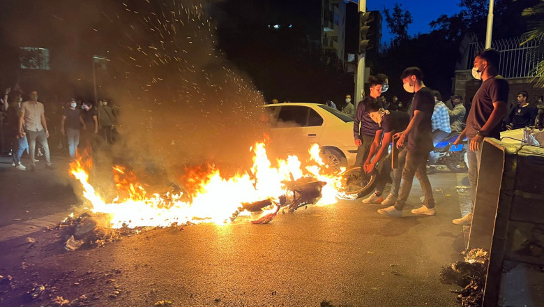 Bărbați care ating o motocicletă în flăcări