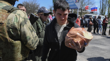 A man carries humanitarian aid in Berdyansk, Zaporozhye region, printre soldati inarmati