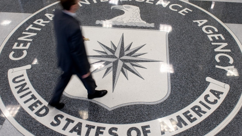 Un om pășește pe sigla CIA din holul de intrare al sediului CIA din Langley, Virginia