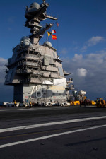 The shadow of an MH-60S Nighthawk attached to the "Tridents" of Helicopter Sea Combat Squadron (HSC) 9 is cast on the first-in-class aircraft carrier USS Gerald R. Ford's (CVN 78) island during an ammunition onload, Sept. 25, 2022. Ford is underway in Atl