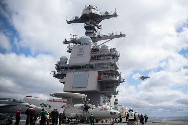 Sailors assigned to Carrier Air Wing (CVW) 8 and USS Gerald R. Ford (CVN 78) conduct flight operations as an E2-D Hawkeye, attached to the "Bear Aces" of Airborne Command and Control Squadron (VAW) 124, flies over the flight deck, March 29, 2022. Ford is