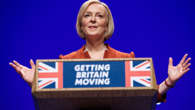 Liz Truss la un podium inscripționat cu textul Getting Britain movement peste steagul regatului unit