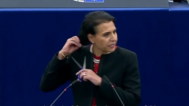 femeie la podiumul PE cu o foarfecă se pregătește să-și taie părul
