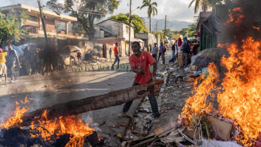 Bărbat care aruncă lemne pe foc la un protest în Haiti