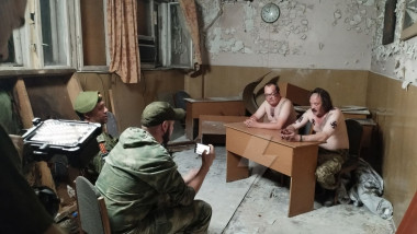 actori in rol de soldati ucraineni la bustul gol, grasi, cu svastici si trident pe piept, interogati de soldati rusi