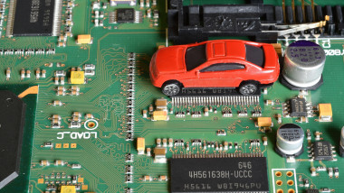 Toy cars on electronic board and microchip. The shortage of microchips and semiconductors creates a shortage of new cars. Conceptual image for semicon