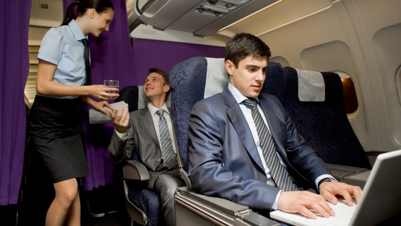stewardesa care zambeste unor pasageri tineri de la clasa business