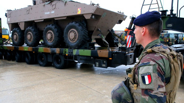 A French soldier stands near an Armored Infantry Fighting Vehicle