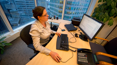 Femeie la birou, lucrează la computer