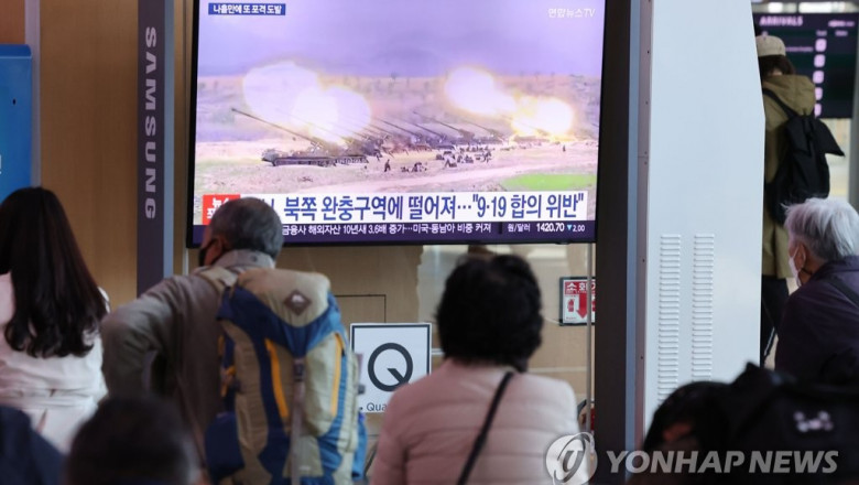 oameni privesc la un ecran cu imaginile conflictului dintre corei