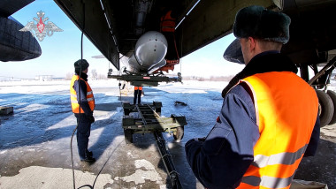 Russian airmen examining a Tupolev Tu-95MS bomber aircraft, with an air-launched cruise missile