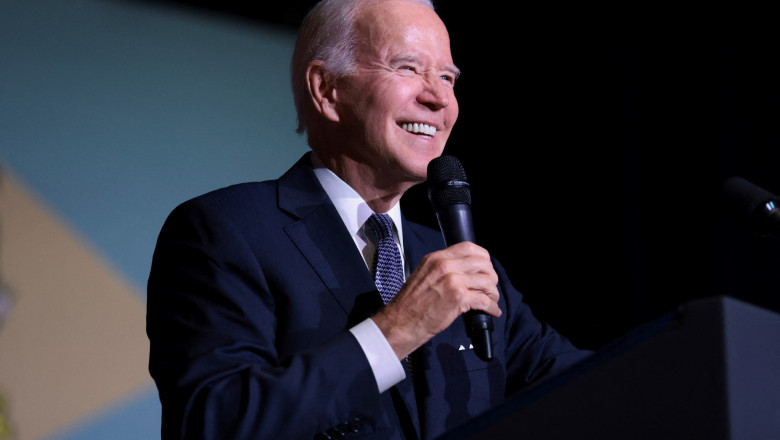 Joe Biden zâmbește vorbind la microfon