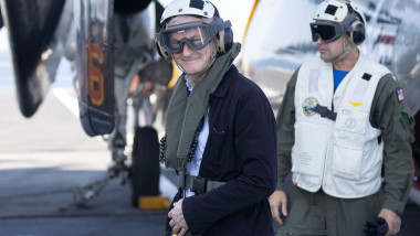 prim-ministrul Norvegiei cu cască de aviator și fular în apropiere de un avion