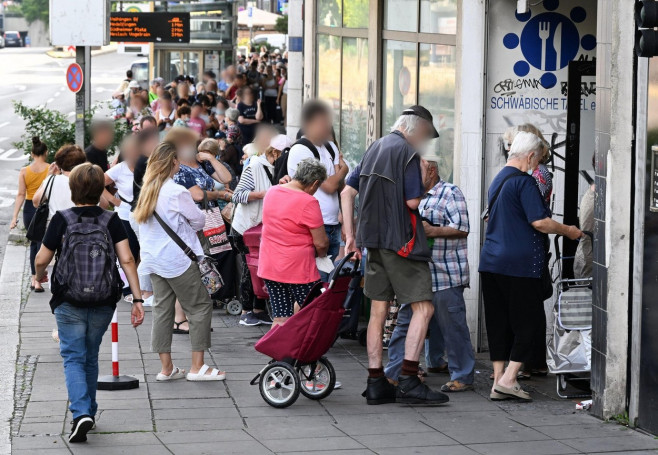 Stuttgart, Germany. 21st July, 2022. People stand in line waiting outside a food bank. Welfare associations have demanded that the green-black state government immediately convene a social summit. Credit: Bernd Weibrod/dpa/Alamy Live News