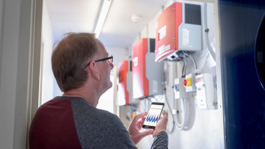 Community worker using smartphone app to check heat pump energy controls