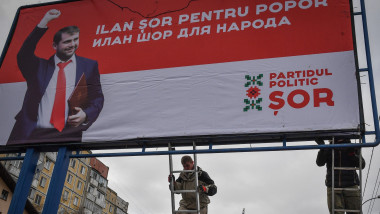 Workers fix an election campaign billboard depicting Moldova's parliamentary candidate Ilan Shor and reading both in Romanian and Russian "Ilan Shor (is) for the people" in Chisinau on