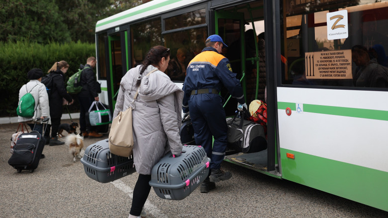 civili ucraineni evacuați din Herson se urcă în autobuz