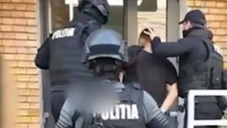 Polițiști care bagă în sediul un bărbat cu cătușe la mâini
