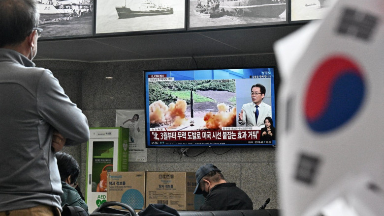 oameni se uita la stiri privind rachetele lansate de coreea de nord